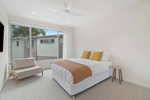 A bedroom with a bed, a sofa, a small stool, and a ceiling fan. - Stonewood by Coast Hosting (North Avoca)