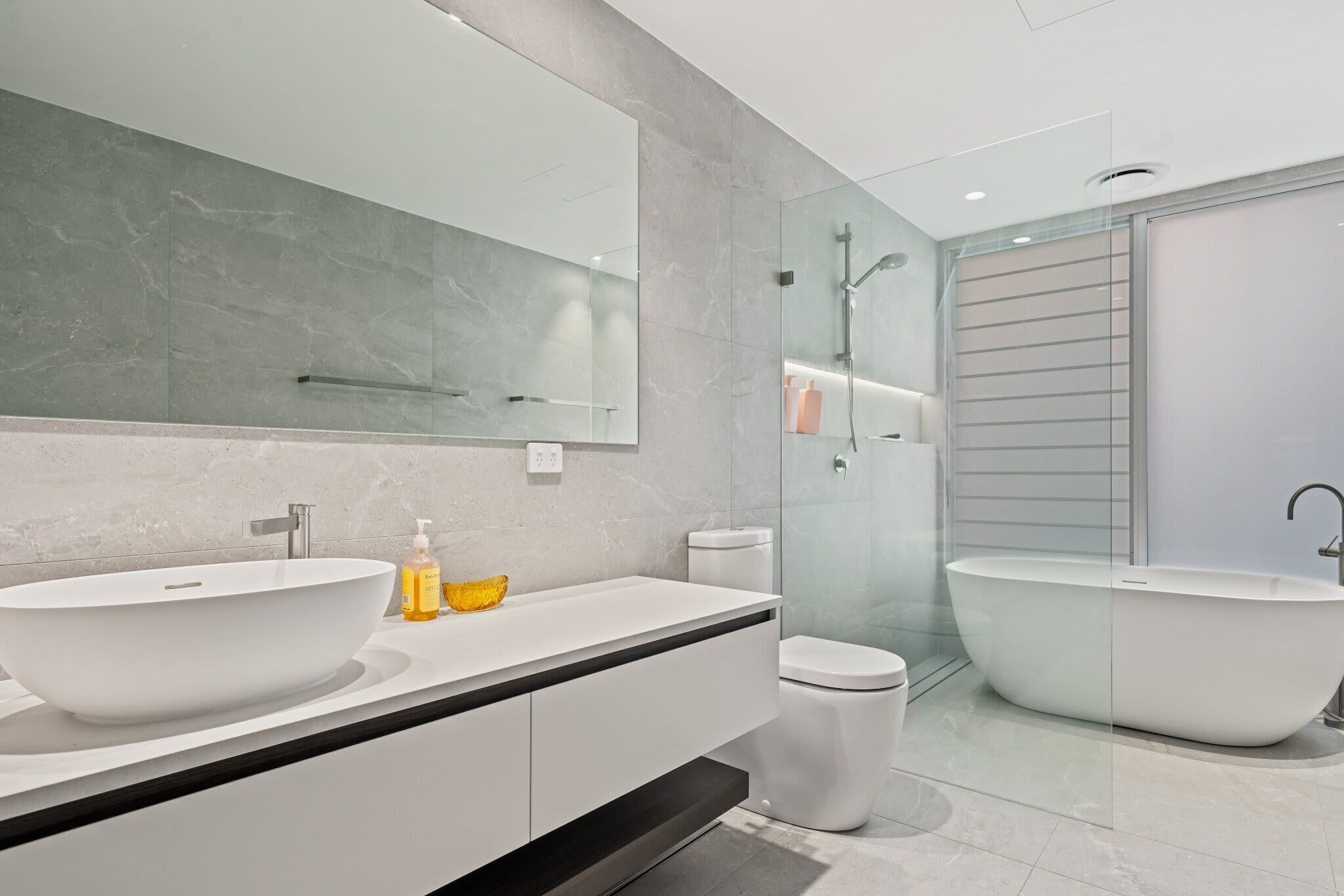 A modern bathroom with a large freestanding bathtub, a vessel sink, and a toilet.