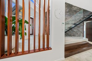 Un interior moderno con barandilla de madera, pared de piedra y escalera.