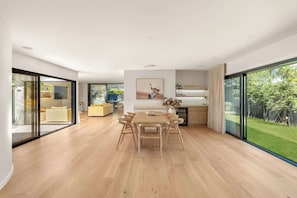 Amplia sala de estar con mesa y sillas, un sofá y una cocina con un gran ventanal.
