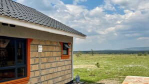 Un edificio de ladrillo con techo de tejas, una ventana con marco de madera y un camino de piedra que conduce a un campo cubierto de césped.