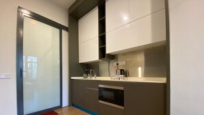 Una cocina moderna con armarios grises, un horno de acero inoxidable y una cafetera sobre la encimera.