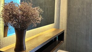 A modern bathroom with a large mirror, a wooden vanity, and a vase of dried flowers. - Transit Samui Resort (Koh Samui)