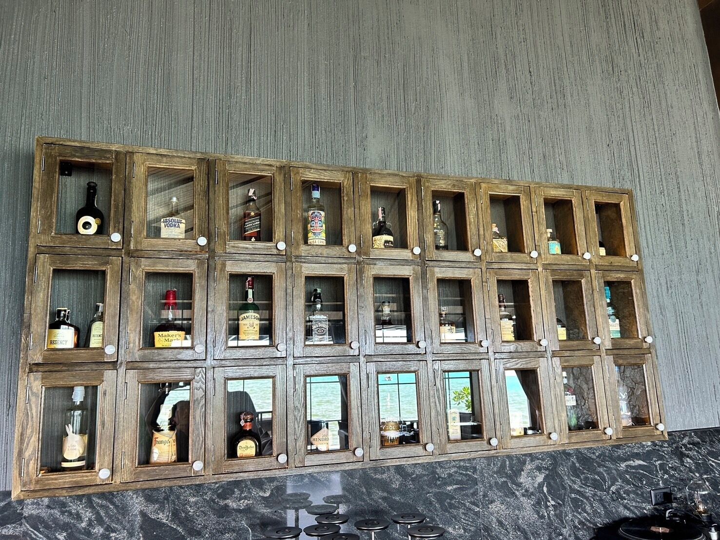 Un mur composé d’armoires en bois dotées de portes en verre, chacune contenant des bouteilles de spiritueux.