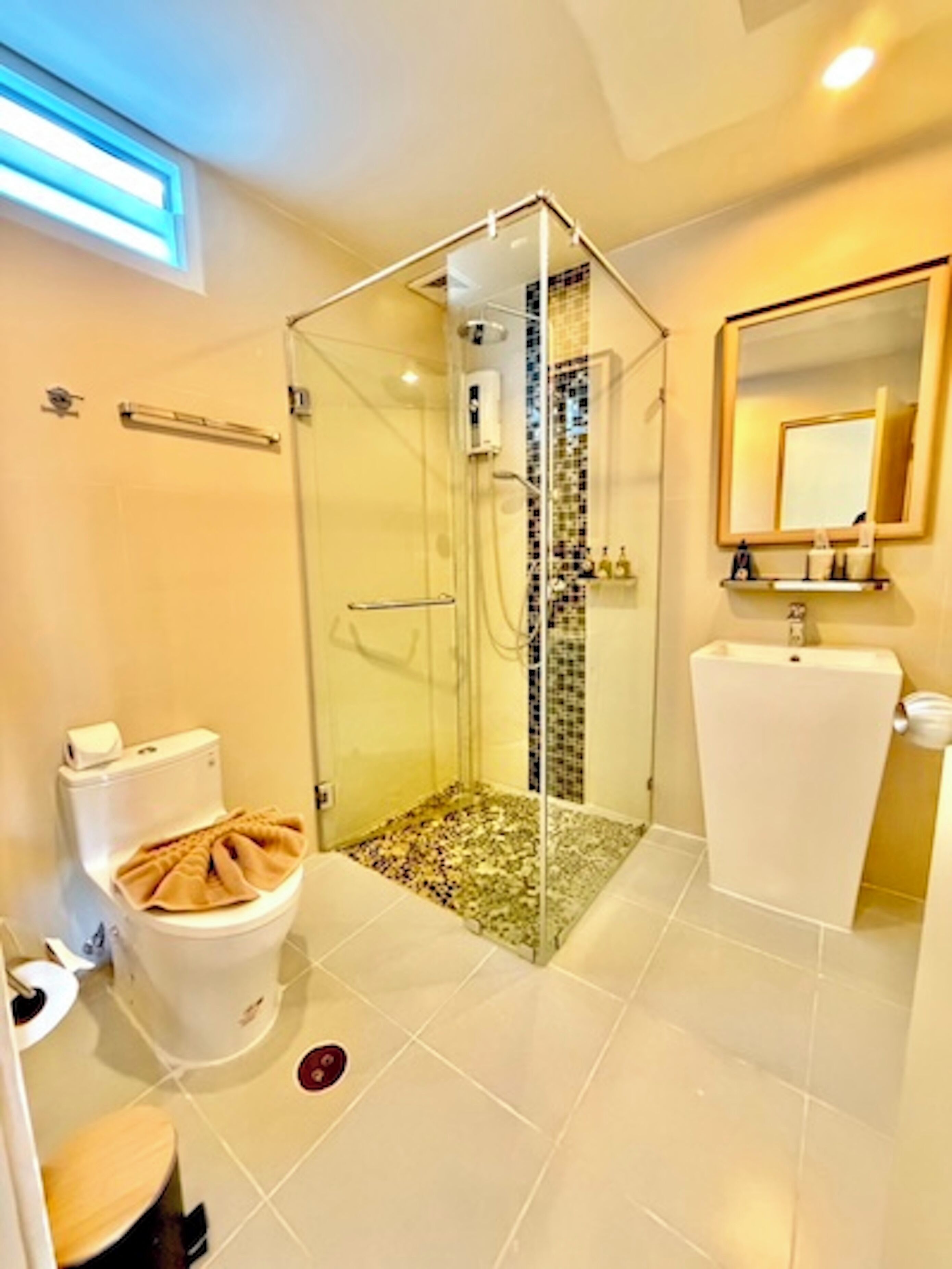 A bathroom with a glass-enclosed shower, a toilet, a sink, and a mirror.