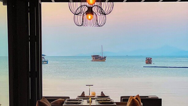A restaurant with tables set for dining, a view of the sea, and a unique hanging light fixture. - Transit Samui Resort (Koh Samui)