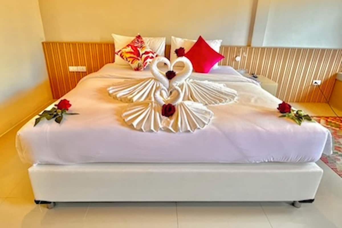 A bed with a swan-shaped bedspread and two roses.