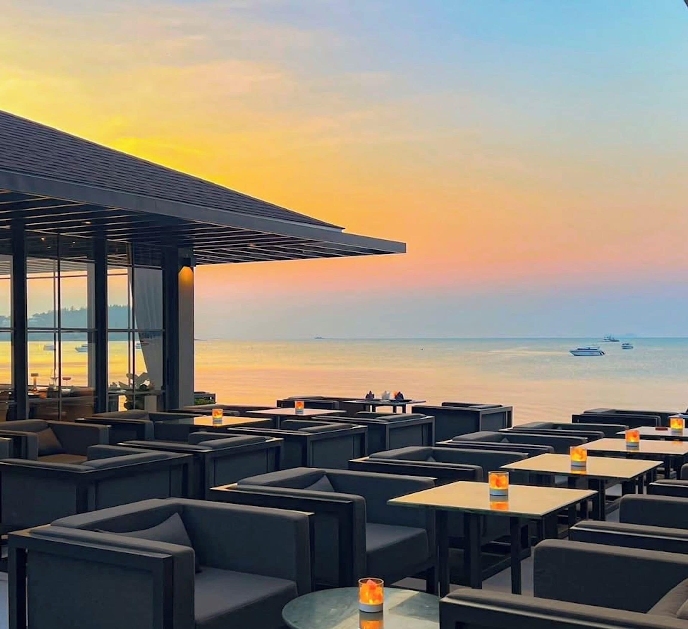 Restaurante à beira-mar com mesas ao ar livre e vista para o oceano.