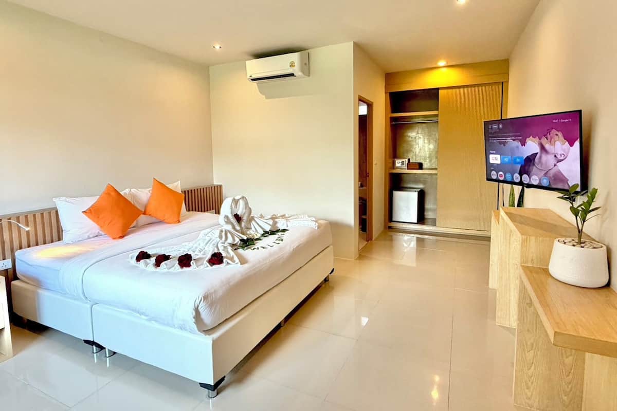 A modern hotel room with a bed, a TV, and a small kitchenette.