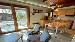 A modern kitchen with wooden cabinets, a dining table, and blue chairs.