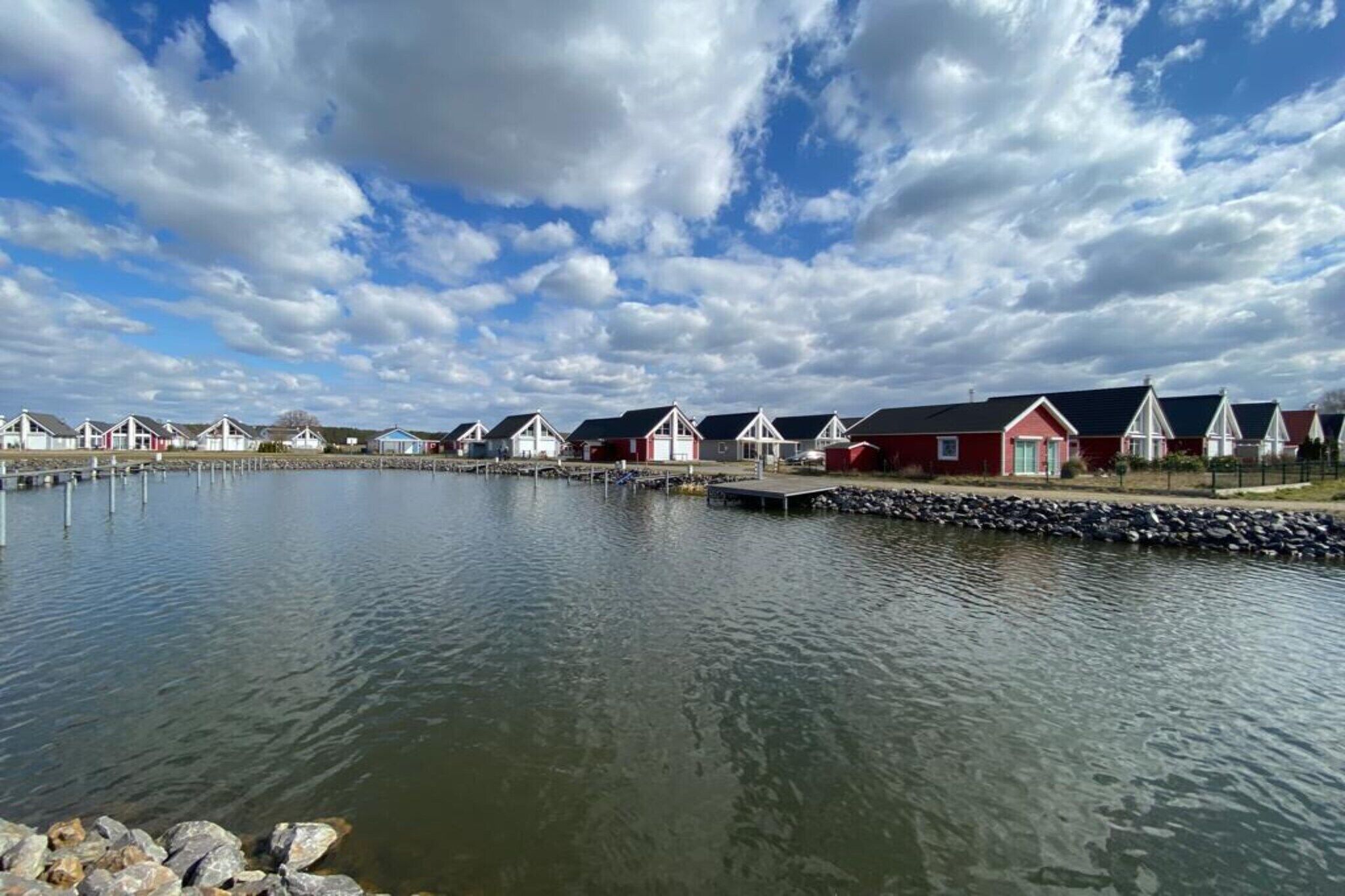 A row of red and white houses by a calm body of water with docks.