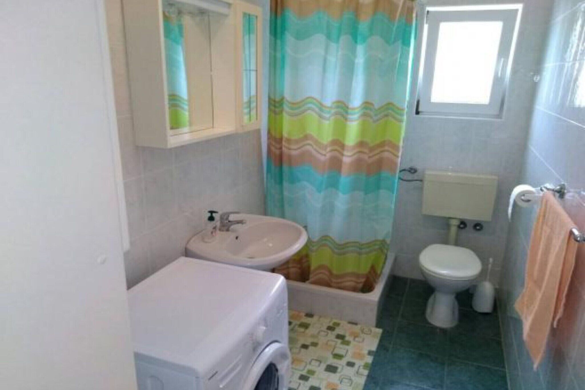 Een kleine badkamer met een wastafel, toilet en een wasmachine.