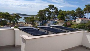 Una azotea con paneles solares, vista al mar y una fila de casas al fondo.
