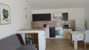 Cocina compacta con comedor, sofá y una pequeña isla con taburetes.