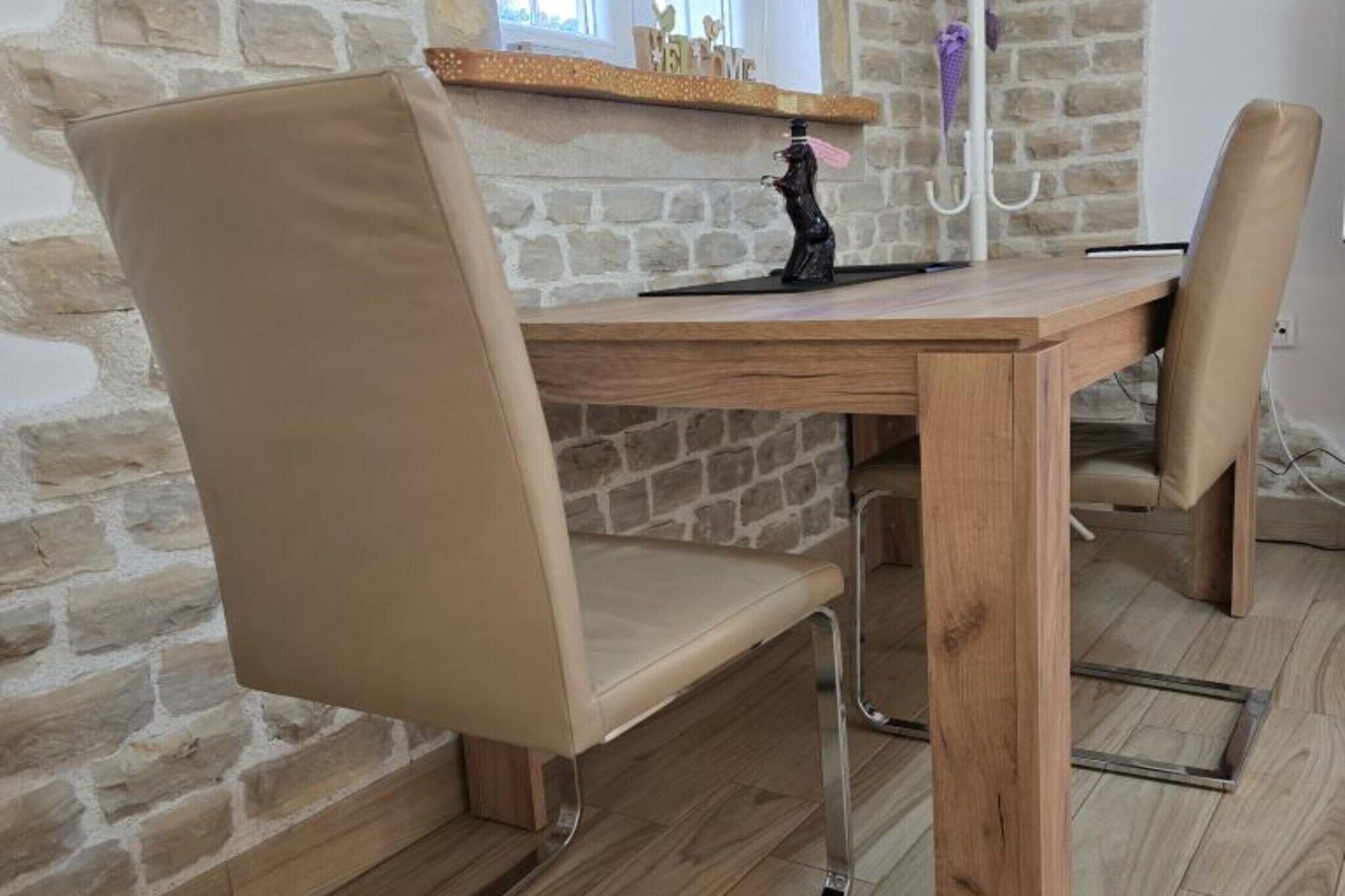 A dining area with a wooden table and two beige upholstered chairs.