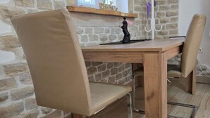 A dining area with a wooden table and two beige upholstered chairs. - Studio apartment Angir Martina (Brodarica)