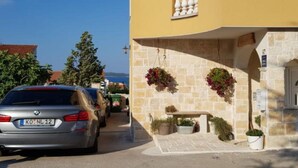 A yellow building with a stone facade, a balcony, and hanging flower baskets. - Studio apartment Angir Martina (Brodarica)