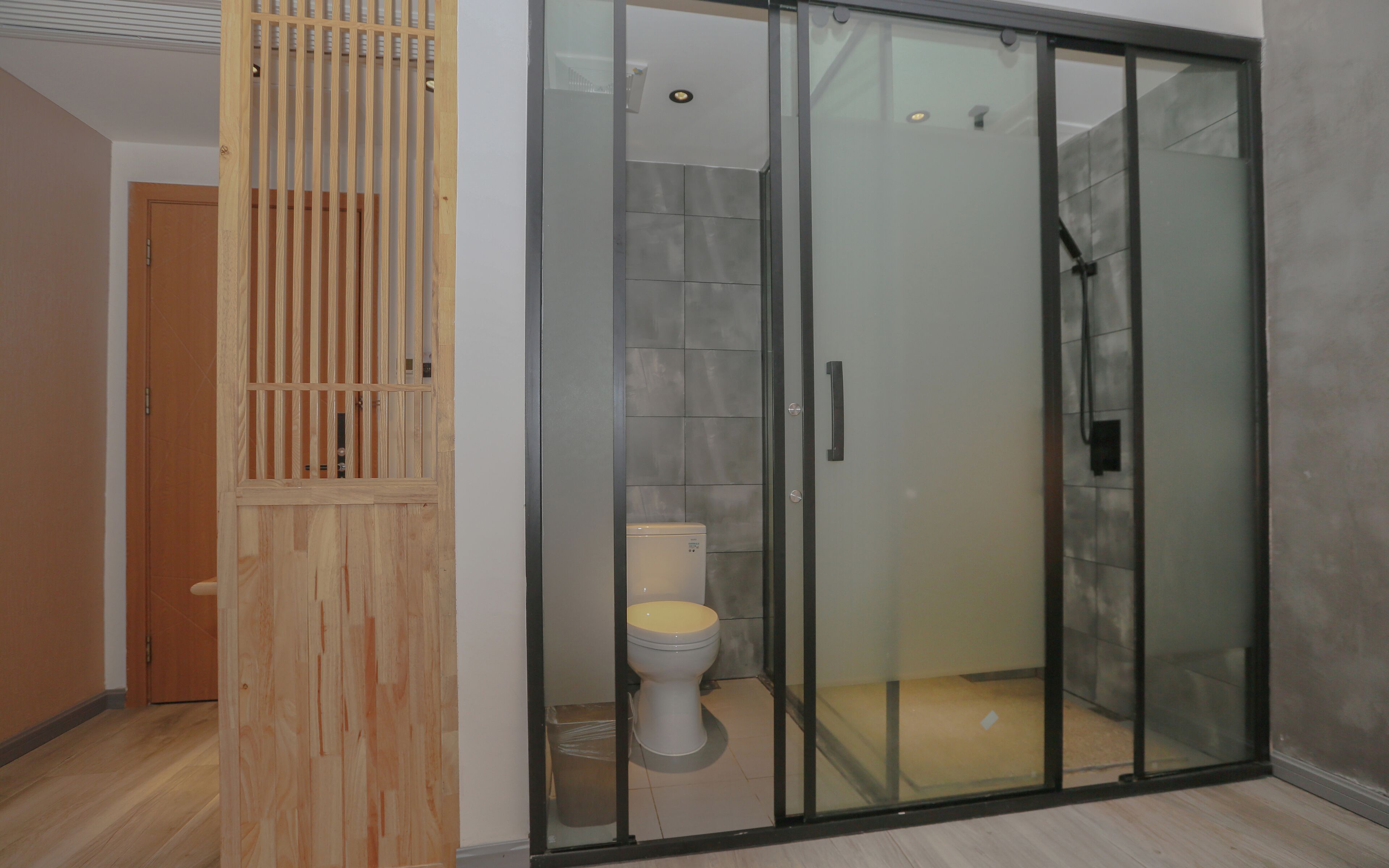 Une salle de bain moderne avec une douche à parois de verre, des toilettes et une cloison en bois.