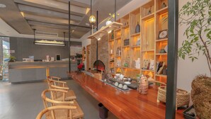 A modern bar area with wooden chairs, a long counter, and shelves with various items. - Cozy Boutique Hotel (Zhangjiajie)