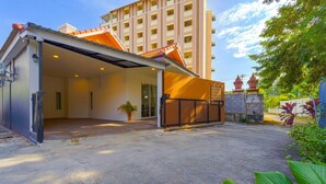 Ein Hotel mit Eingangsbereich, überdachter Außenanlage und einem befestigten Zugang. Im Hintergrund sind traditionelle architektonische Elemente zu sehen.