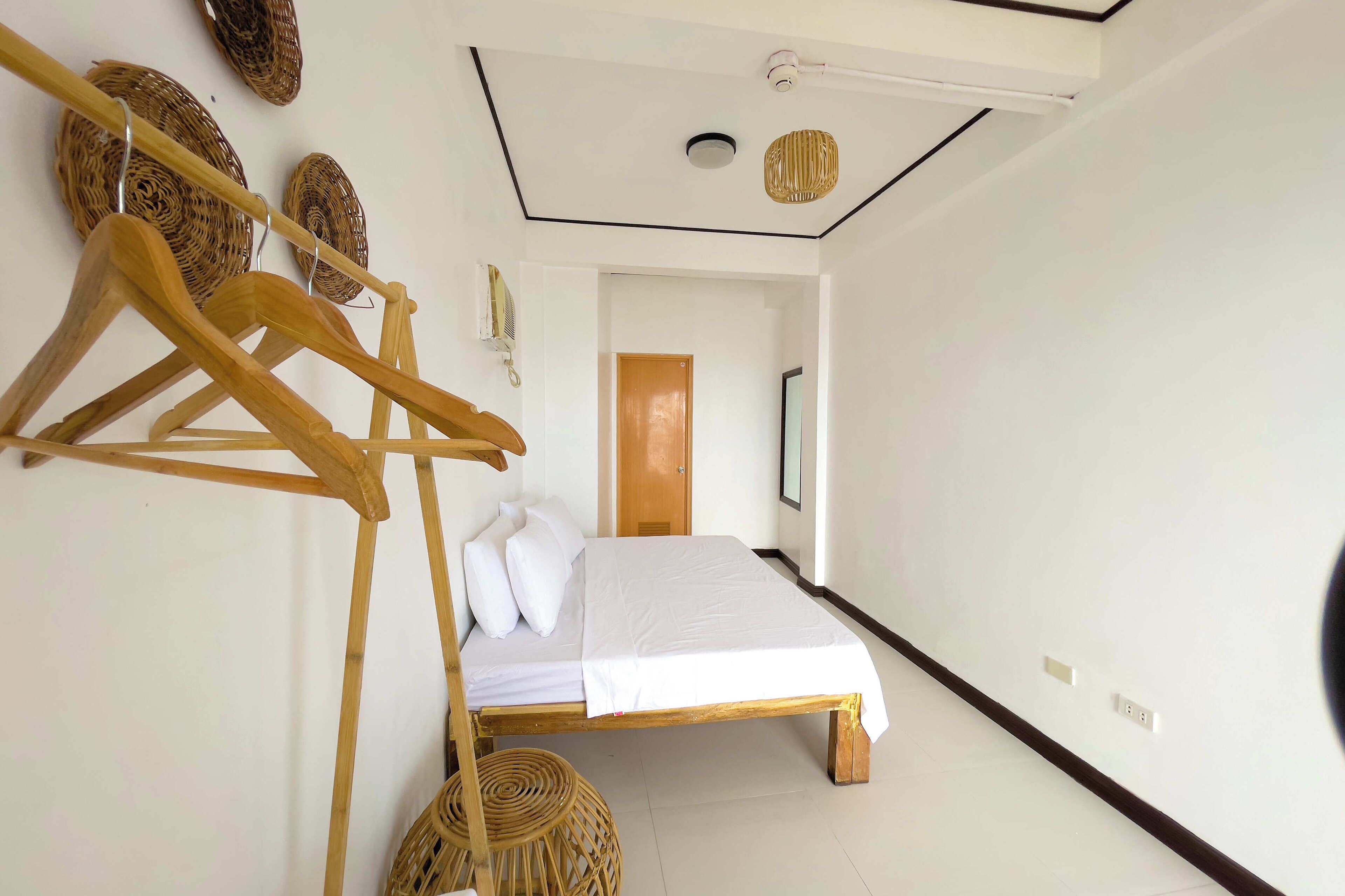 Ein Schlafzimmer mit einem Holzbett, weißer Bettwäsche, einem Wäscheständer aus Holz und gewebten Körben.