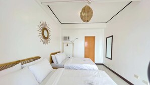A hotel room with two beds, a ceiling fan, a wall-mounted air conditioner, and a wooden door. - Salacia Beachfront Resort (Bauan)