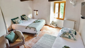 Un dormitorio con cama, una silla, un ventanal y un radiador.