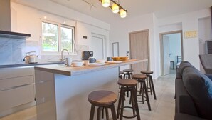 Een moderne keuken met een marmeren aanrechtblad, barstoelen en een groot kookeiland.