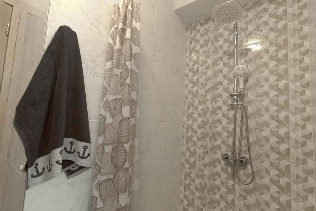 A bathroom with a shower, tiled walls, and a towel hanging on the wall.