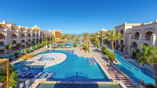 Un resort con una amplia piscina central, diversas zonas de natación y una variedad de opciones de descanso.