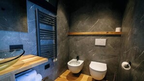 A modern bathroom with a bidet, toilet, and a glass sink. - Charming bungalow in phenomenal Brenzone sul Garda with AC (Brenzone sul Garda)