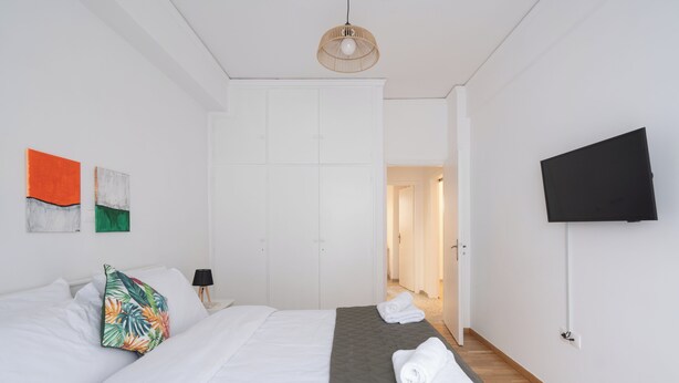 Una camera d'albergo con un letto, una televisione e un ingresso che dà su un'altra stanza.