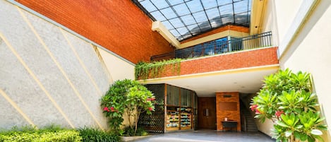 Un bâtiment moderne doté d’un toit en verre, de murs en briques et d’un escalier central menant à un balcon situé au deuxième étage.