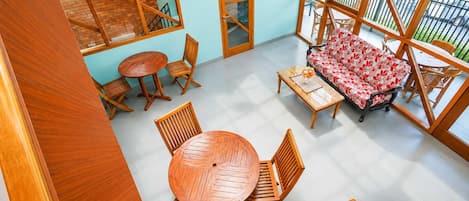 Un balcón amplio con mobiliario de madera, una mesa redonda y un sofá estampado con motivos florales.