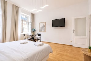 Een hotelkamer met een bed, een bureau, een stoel, een televisie en een deur.
