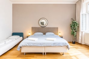 Een slaapkamer met een bed, nachtkastjes, een spiegel, een kamerplant en een raam.