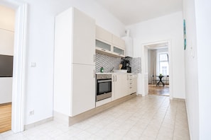 Eine moderne Küche mit weißen Schränken, einem Einbauofen und einer Kaffeemaschine.