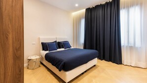 A modern bedroom with a large bed, a marble bedside table, and a wooden floor. - Blue Santa Croce by MMega (Florence)