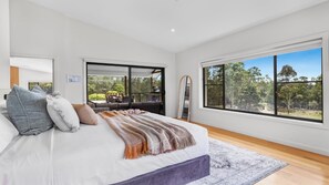 Quarto com uma cama grande, vista do exterior por uma porta de correr e uma janela ampla.