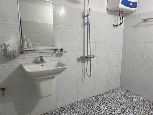 Een badkamer met een wit wastafel, een spiegel, een douche en een betegelde vloer.