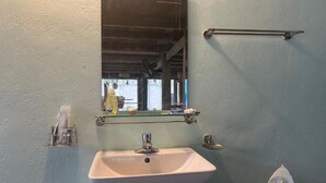 Une salle de bain avec un lavabo blanc, un miroir et des toilettes.