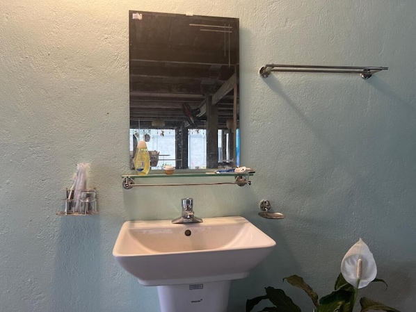 Egy fürdőszoba, amelyben fehér mosdókagyló, tükör és WC található.