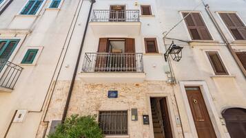 Un edificio de varios pisos con balcones, fachada de piedra y un letrero azul que indica la dirección.