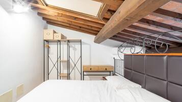 A bedroom with a bed, a nightstand, a dresser, and a skylight.