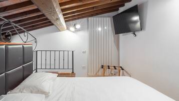 Une chambre à coucher avec un lit, un téléviseur fixé au mur et un plafond en bois.