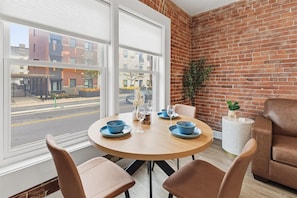 Un coin repas avec une table ronde, des chaises et un mur en briques.
