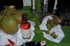 Un tavolo con una bottiglia, dei cocco e un cesto di lime.