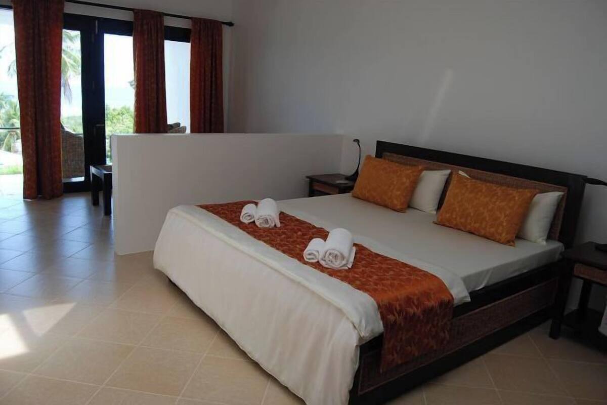 Ein Hotelzimmer mit Bett, Nachttisch, Sessel und Blick ins Freie.