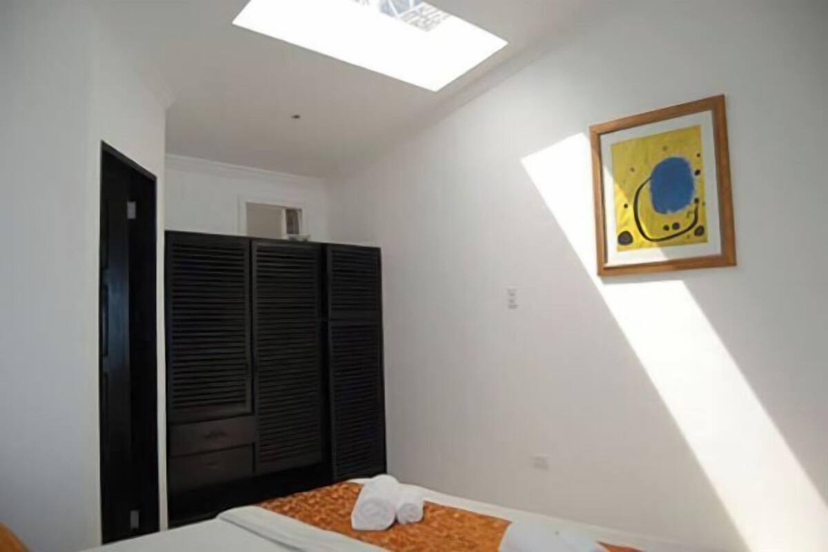 Ein Schlafzimmer mit Bett, Kleiderschrank, Dachfenster und einem gerahmten Kunstwerk an der Wand.