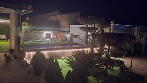 Ein Außenpoolbereich mit Steinmauer, Basketballkorb und gut beleuchtetem Eingang.